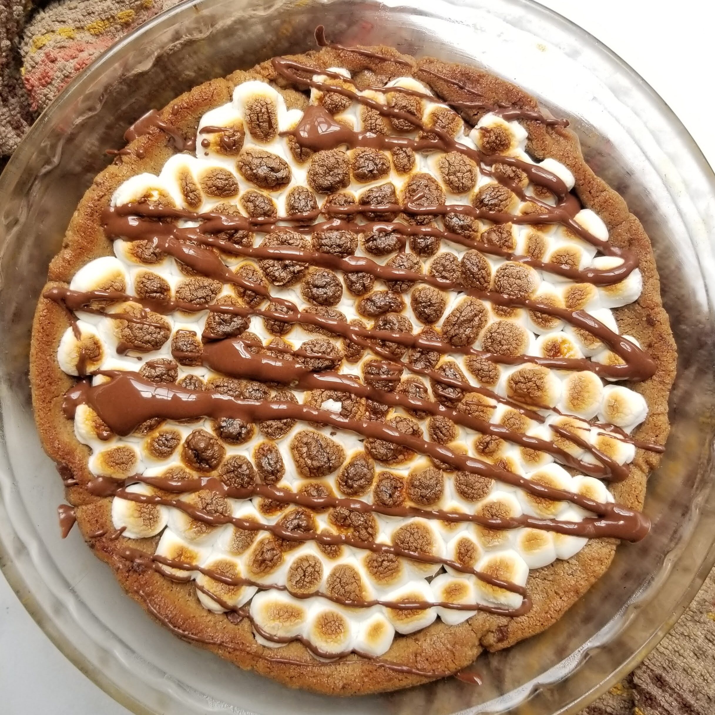 Overhead view of gluten free s'mores cookie cake with toasted marshmallows and chocolate drizzle