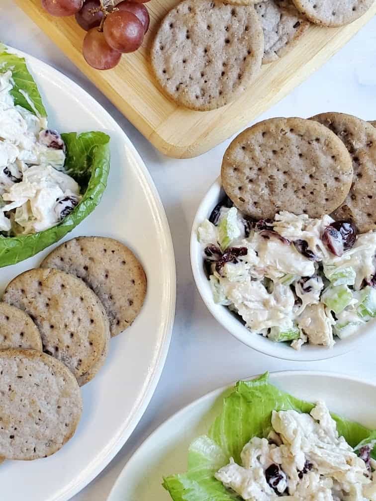 Healthy harvest chicken salad with apples and cranberries in a white bowl with gluten free crackers