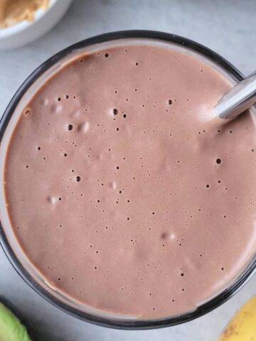 Creamy peanut butter cup smoothie in a glass, made with cocoa, peanut butter, and dairy-free milk, and peanut butter for a high protein gluten-free healthy treat.