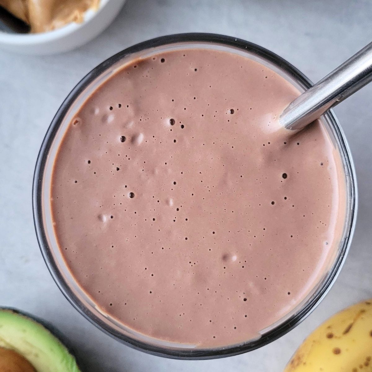 Creamy peanut butter cup smoothie in a glass, made with cocoa, peanut butter, and dairy-free milk, and peanut butter for a high protein gluten-free healthy treat.