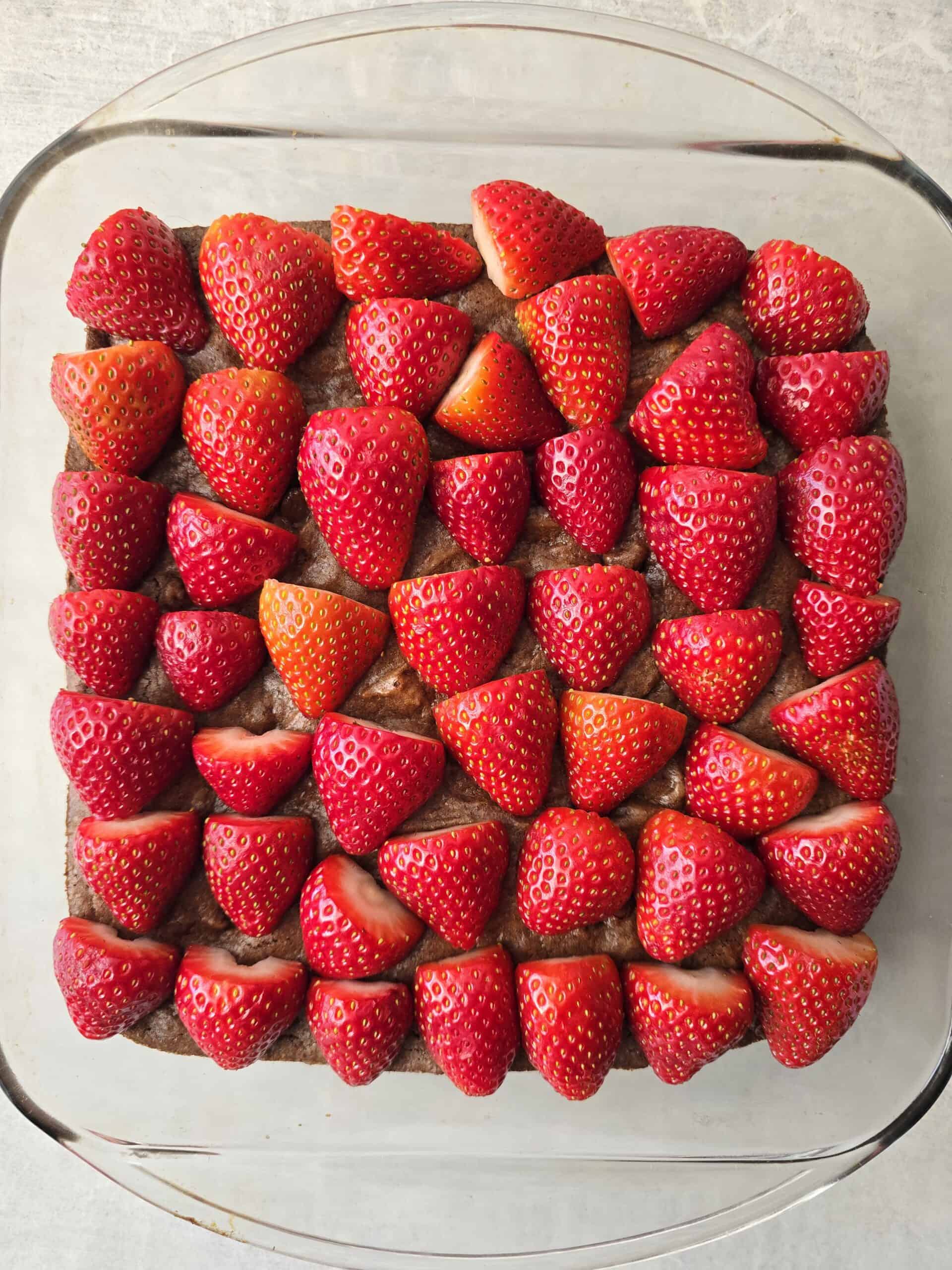 Arranging fresh strawberries on cooled gluten free brownies