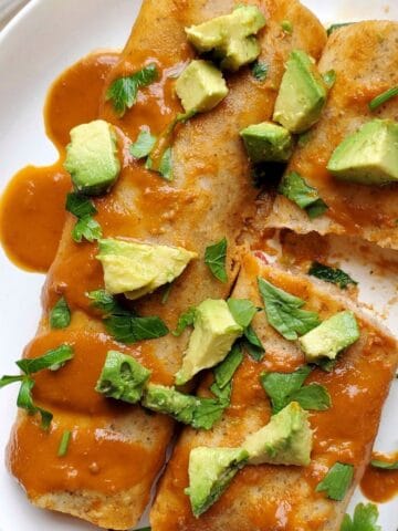 Gluten free beef enchiladas made with ground beef, refried beans, and melted cheese baked in enchilada sauce.