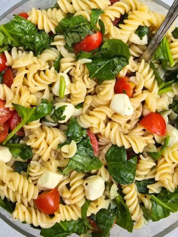 Fresh caprese pasta salad with spinach and basil coated in balsamic vinaigrette with gluten free pasta