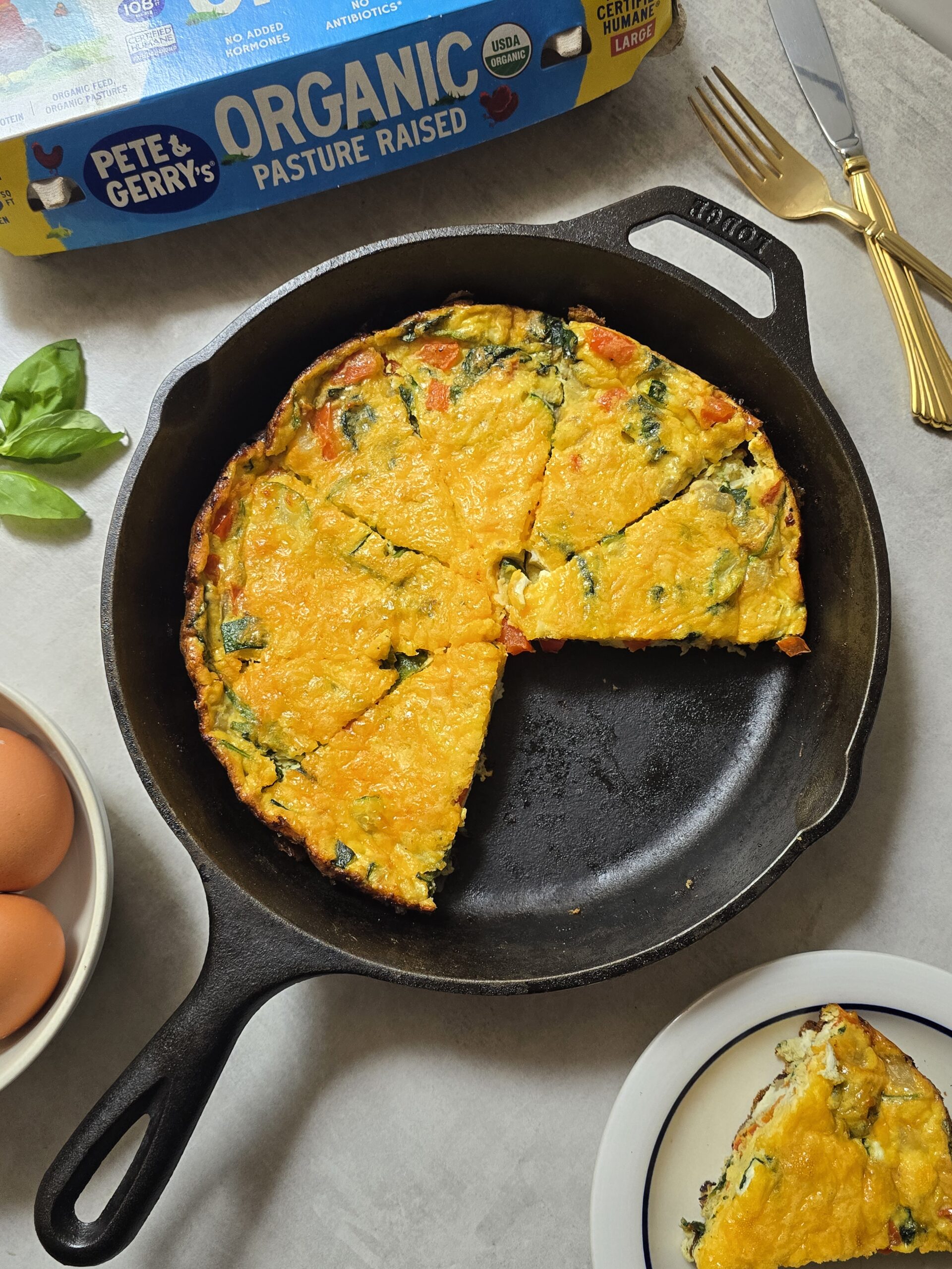 Freshly baked veggie frittata made with zucchini, red pepper, onion, basil, and melted cheese in a cast iron skillet.