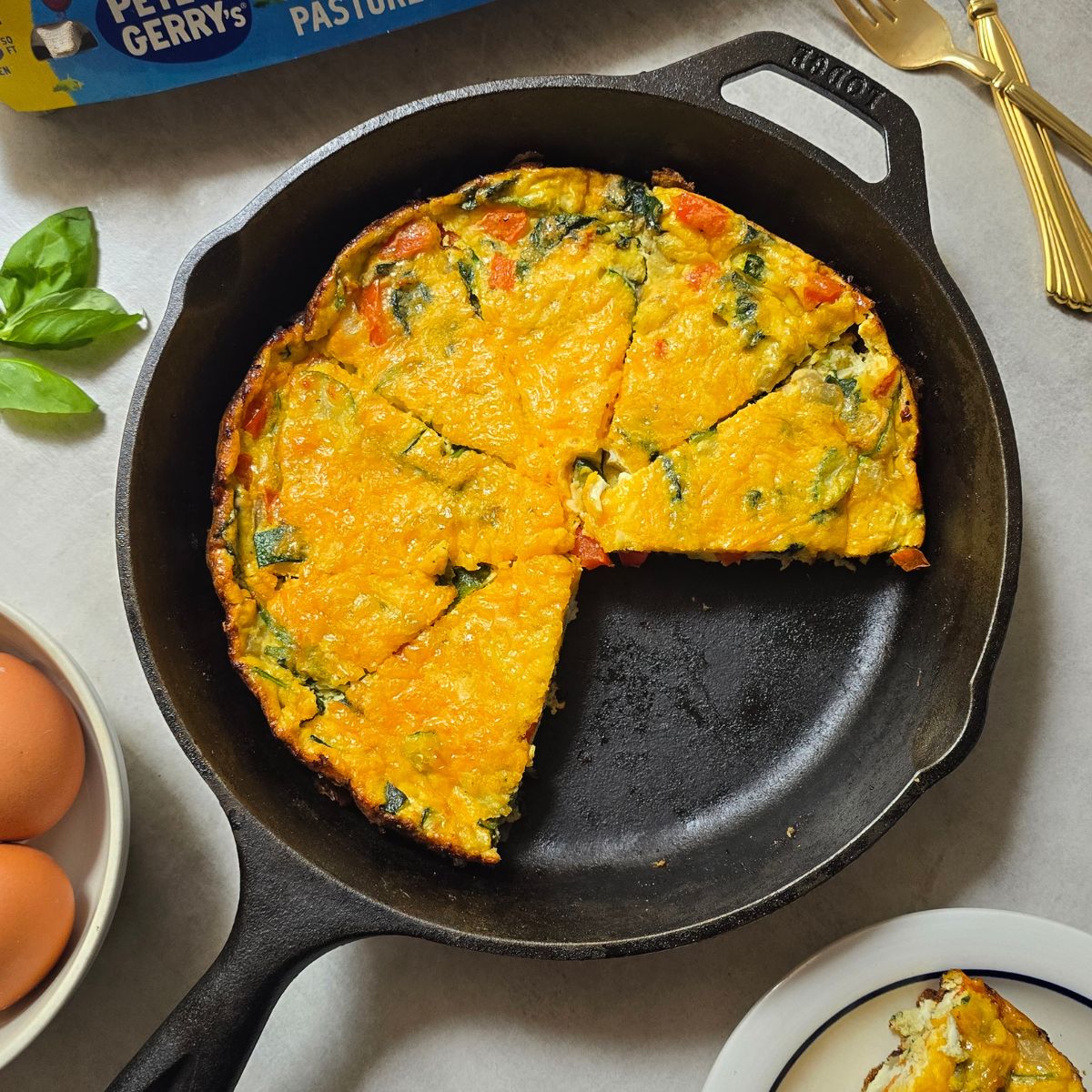 Freshly baked veggie frittata made with zucchini, red pepper, onion, basil, spinach and melted cheese in a cast iron skillet.