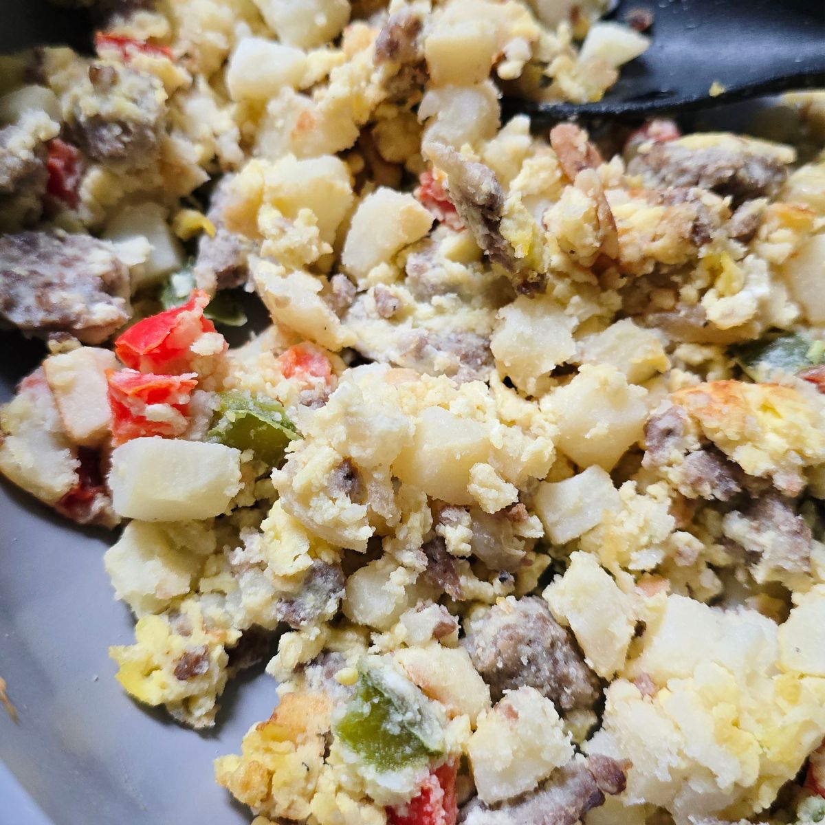 gluten free Sausage breakfast scramble with eggs, potatoes, peppers, and onions in a skillet