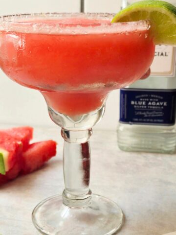 Frozen watermelon margarita served in a salt-rimmed glass with fresh watermelon and lime garnish, a refreshing gluten-free summer cocktail.