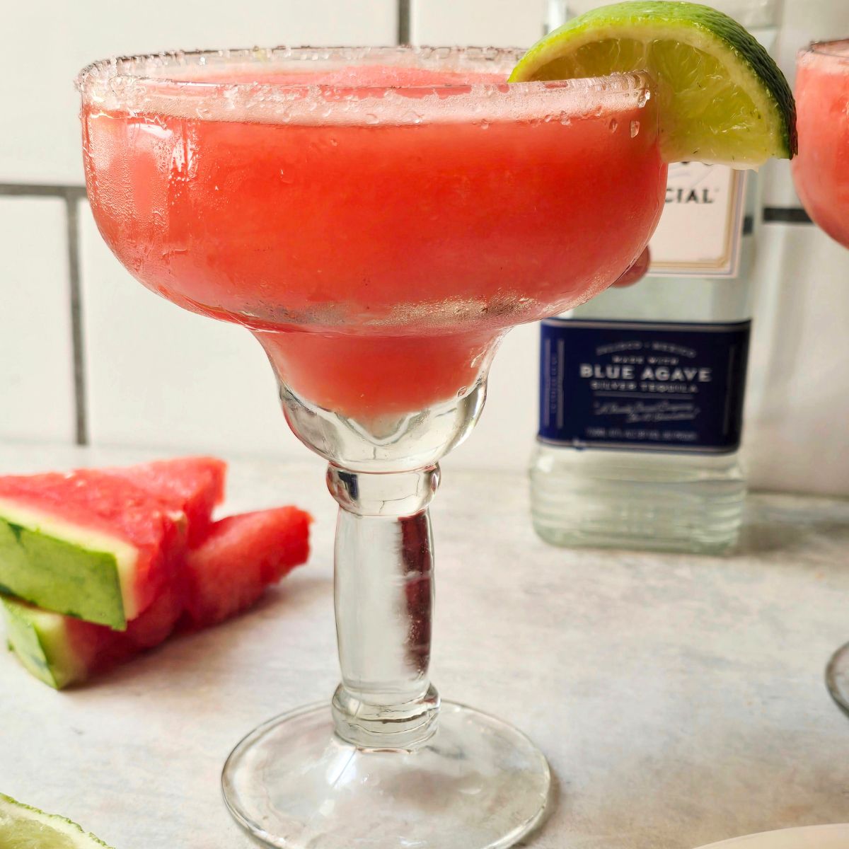 Frozen watermelon margarita served in a salt-rimmed glass with fresh watermelon and lime garnish, a refreshing gluten-free summer cocktail.