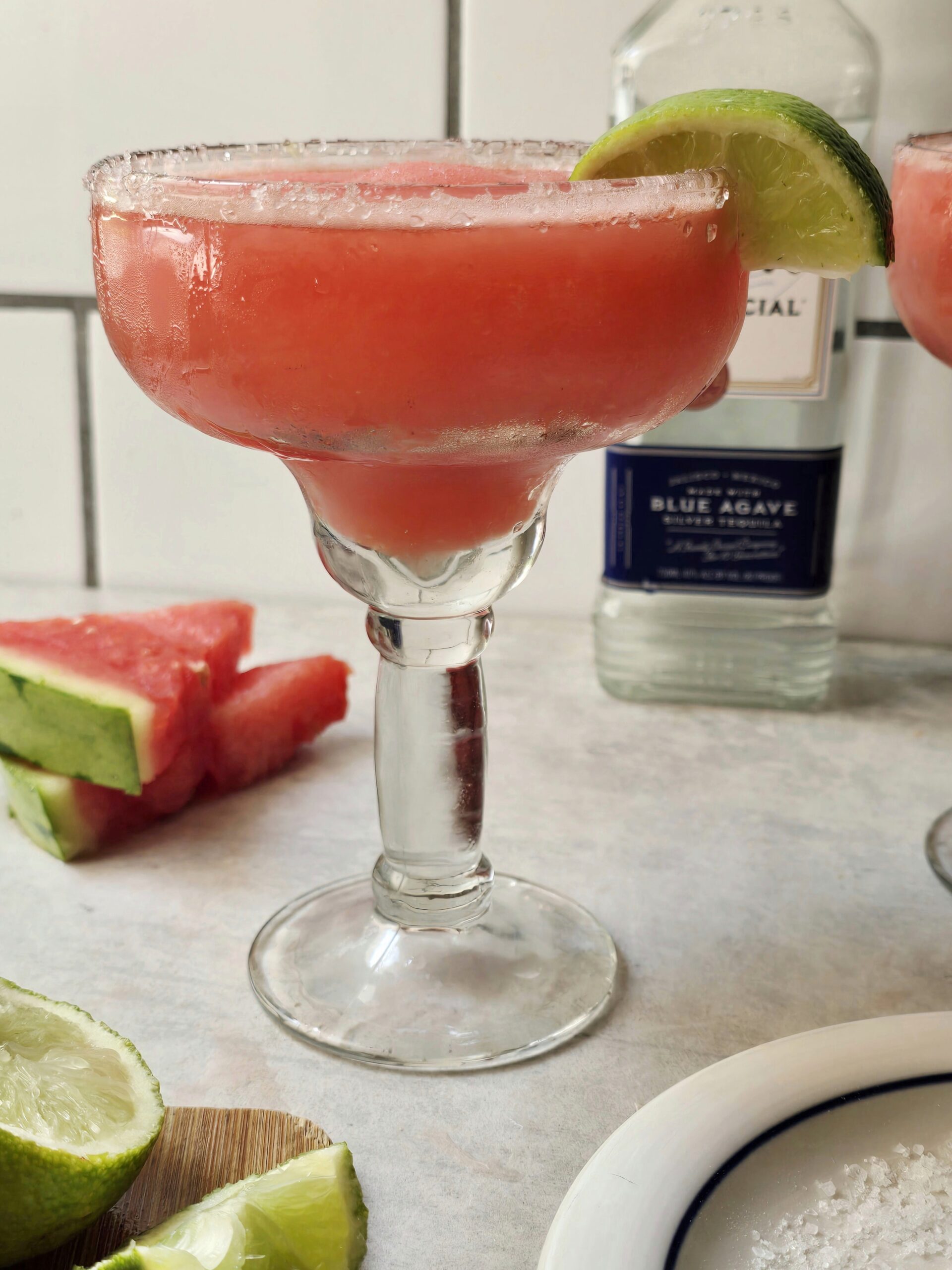 Frozen watermelon margarita served in a salt-rimmed glass with fresh watermelon and lime garnish, a refreshing gluten-free summer cocktail.