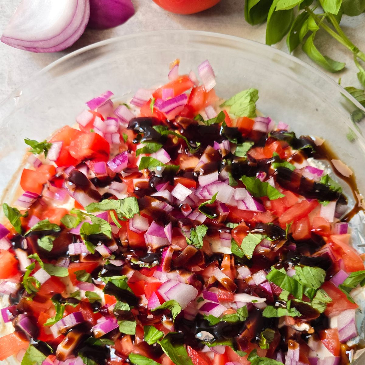 Gluten free summer appetizer featuring creamy garlic herb cheese topped with tomatoes, onions, basil, and balsamic glaze.