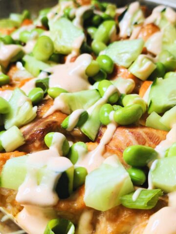 Gluten free salmon sushi bake topped with cucumber, edamame, avocado, green onions and spicy mayo