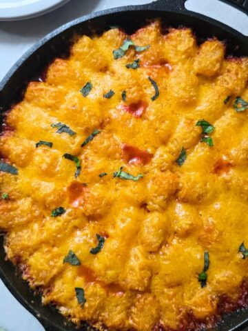 Gluten free sloppy joe tater tot casserole topped with melted cheddar cheese