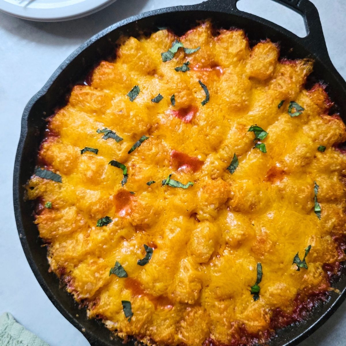 Gluten free sloppy joe tater tot casserole topped with melted cheddar cheese