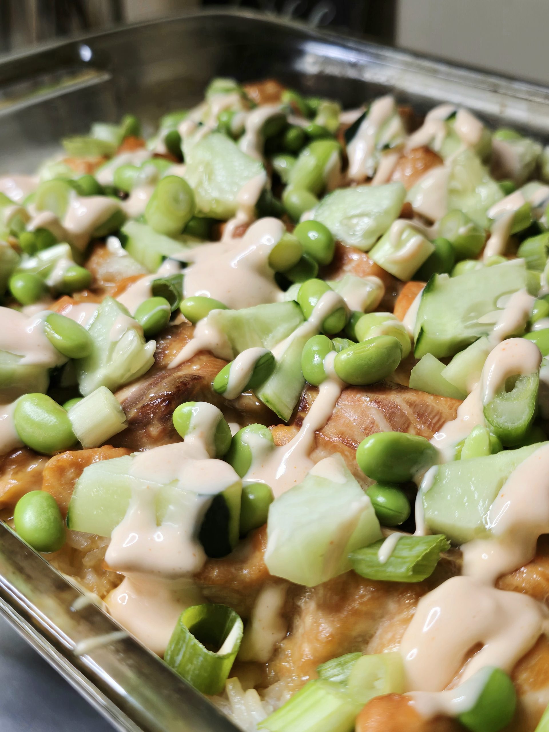 Gluten free salmon sushi bake topped with cucumber, edamame, avocado, green onions and spicy mayo