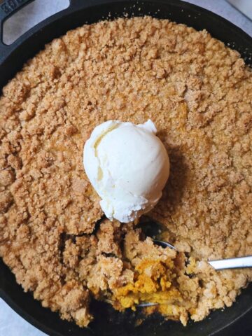 Gluten free pumpkin crisp with creamy pumpkin filling and golden oat topping served in a baking dish